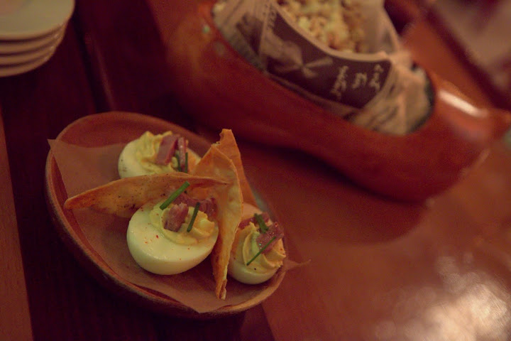 Deviled eggs and smoked duck popcorn in a wooden Gascon shoe