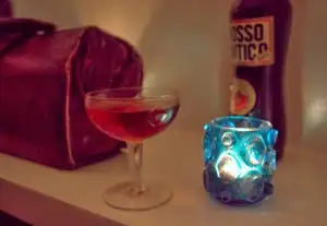 Sipping a whiskey cocktail next to shelf artifacts